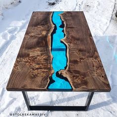 a wooden table with blue water in the middle and snow on the ground behind it