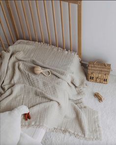 an unmade crib with blankets and toys on the floor