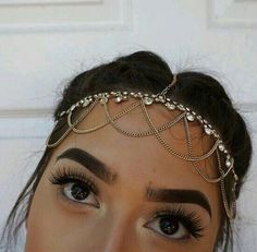 a close up of a woman wearing a head piece with pearls on it's forehead