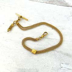 This gorgeous antique Victorian double pocket watch chain with slide is crafted from gold filled metal. It has a rich look of solid gold. It features two lengths of tight curb links, a square slide, a double chain drop, a T bar, and a dog clip, giving you many options.The chain has a nice weight of 14.3 grams and measures almost 12 inches long from the dog clip to the T bar. The double chain drop for your fob is approximately 1 inch long.The length allows you to wear it double around the wrist. Dog Clip, Pocket Watch Chain, Double Chain, Watch Chain, Pocket Watch, Gold Filled, Solid Gold, Chain, Gold