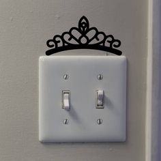 a white light switch with a black crown on it