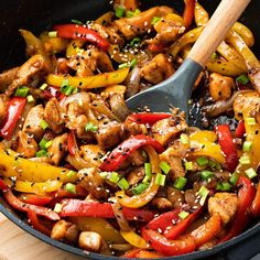 chicken and peppers in a skillet with a wooden spatula on the side, ready to be eaten