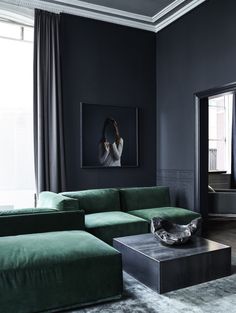 a living room with black walls and green furniture