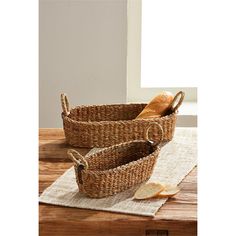 two woven baskets sitting on top of a wooden table next to bread and an apple