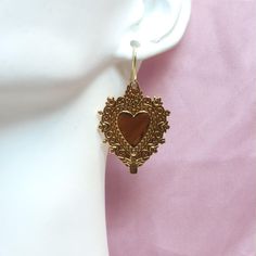 The Divine Heart Earrings feature gold-colored stainless steel pendants inspired by the iconic Sacred Heart imagery. The hooks are crafted from 14k hypoallergenic gold, while the pendants are made from tarnish-resistant stainless steel, ensuring both comfort and durability. Perfect for those who appreciate meaningful design and lasting quality. 14k Hypoallergenic Gold Hooks Earring Pendant Measurement: 30x23mm Tarnish Resistant With Love From Texas Tarnish Resistant Brass Plug Earrings As Gift, Hypoallergenic Gold-tone Brass Jewelry, Brass Heart Charm Dangle Jewelry, Heart Charm Dangle Jewelry In Brass, Gold Plated Heart Pendant Earrings As Gift, Gold Plated Heart Pendant Earrings For Gift, Gold Plated Heart Shaped Pierced Earrings, Yellow Gold Metal Earrings For Valentine's Day, Gold-tone Jewelry As A Gift