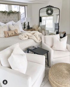 a bedroom with white furniture and pillows on the bed in front of a large mirror