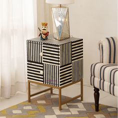 a black and white striped cabinet with a mirror on top next to a blue chair