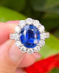 a close up of a person holding a ring with a blue and white diamond in it