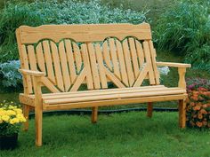 a wooden bench sitting on top of a lush green grass covered park area next to flowers