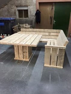 a table made out of wooden pallets sitting on top of a cement floor next to a green door