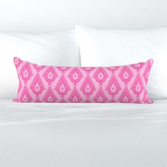 a pink and white pillow sitting on top of a bed