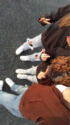 four people sitting on the ground with their cell phones in their hands and one person standing next to them