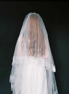 a woman wearing a white veil and wedding dress