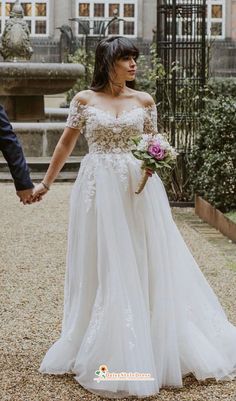 a bride and groom holding hands in front of a building