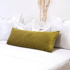 a bed with white sheets and pillows on top of it, next to a wall hanging