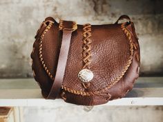 a brown leather purse sitting on top of a shelf