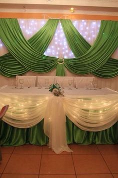 a banquet table set up with white linens and green drapes