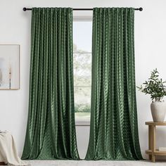 a green curtain hanging in front of a window with a potted plant next to it