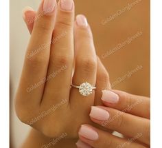 a woman's hand with a ring on her finger and a diamond in the middle