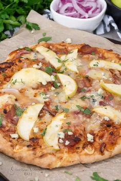 a pizza sitting on top of a wooden cutting board next to a bowl of vegetables