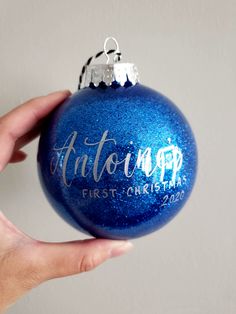 a hand holding a blue ornament with the word autographed on it