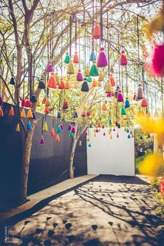 an outdoor area with many colorful objects hanging from the trees