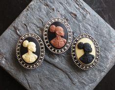 Beautiful African cameos set in detailed antique silver. Cameos feature a detailed African woman with broad shoulders, earrings and a necklace adorning her neck. Choose from cream and black, brown and black or black and cream cameos. Details: *Measures approx 28mm x 18mm *Secure pin back *Cameo is made of a hard, matte resin *Setting is plated brass *Back is lightly textured *Lightweight *Please note these brooches are significantly smaller than my regular size brooches, this size difference can Elegant Black Cameo Brooches, Victorian Style Brooches For Gift, Cabochon Brooches As A Gift, Kwanzaa Gifts, Marine City, Black Cameo, Green Brooch, Broad Shoulders, Cameo Jewelry