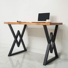 a laptop computer sitting on top of a desk next to a wooden table with metal legs