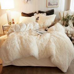 a bed with white fur on it in a bedroom next to two lamps and pictures