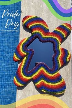 a multicolored knitted object sitting next to a swimming pool