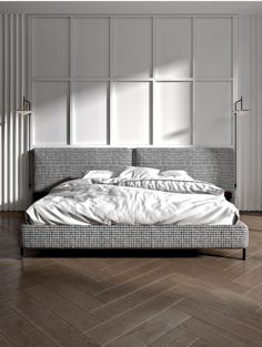 a bed sitting on top of a wooden floor next to a wall with white walls