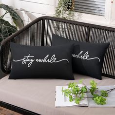 two black pillows sitting on top of a couch next to a potted green plant