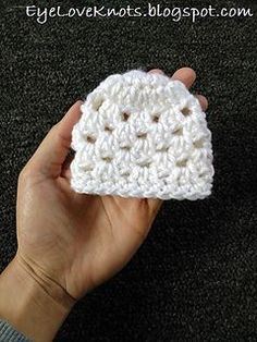 a hand holding a small white crocheted object