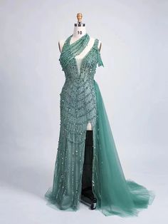 Elevate your evening wardrobe with this enchanting, emerald green gown that exudes sophistication and grace. Crafted with meticulous attention to detail, this dress features an intricate beading design that cascades down the bodice, adding a touch of shimmering allure. The one-shoulder neckline creates an asymmetrical elegance, drawing the eye to the décolletage and providing a modern twist on classic couture.The flowing skirt is designed from layers of soft tulle, offering a subtle transparency that adds an ethereal vibe to your ensemble. The thigh-high slit not only enhances the dress’s sultry appeal but also ensures effortless movement and a comfortable fit for all-night wear. Whether youre gracing a red carpet, attending a gala, or wowing guests at a formal event, this dress guarantees Green Ball Gown With Sweep Train For Banquet, Elegant Green Ball Gown With Sweep Train, Green Ball Gown With Sweep Train For Gala, Green Floor-length Ball Gown With Sweep Train, Fitted Green Ball Gown For Gala, Dark Green Sequin Party Dress, Green Evening Dress With Sweep Train For Banquet, Green Evening Dress With Sweep Train For Prom, Green Ball Gown Evening Dress For Prom