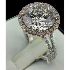 a fancy ring with an oval cut diamond surrounded by smaller round diamonds and gold accents