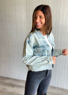 Cropped washed denim jacket with raw hem, trucker jacket detailing with two front chest pockets, and shanks at cuffs for closure. Illinois logo application is embroidered on the arm sleeve and chenille back. Officially licensed. Denim jacket does have some distressing. Show styled with the KanCan Ultra High Rise Black 90s Boyfriend Jeans. & Navy Claw Clip. Material: 100% Cotton Model: Wearing a size small. Fits true to size, but if you are in between sizes or if you plan to layer heavily, we rec Acid Wash Outerwear With Frayed Hem For Fall, Faded Cotton Outerwear With Frayed Hem, Trendy Medium Wash Denim Jacket With Frayed Hem, Relaxed Fit Medium Wash Denim Jacket With Frayed Hem, Faded Cotton Denim Jacket With Frayed Hem, Light Wash Cotton Denim Jacket With Frayed Hem, Trendy Relaxed Fit Denim Jacket With Frayed Hem, Acid Wash Denim Jacket With Frayed Hem For Fall, Trendy Denim Jacket With Frayed Hem And Relaxed Fit