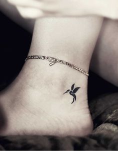 a small tattoo on the ankle of a woman's foot, with a bird