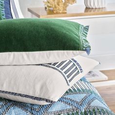 four pillows stacked on top of each other in front of a bed with blue and green sheets