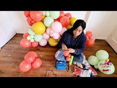 a woman sitting on the floor with balloons and confetti in front of her