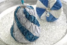 two blue and white ornaments sitting on top of a silver plate