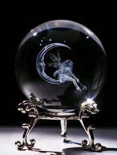 a crystal ball with a fairy sitting on it's side and the moon behind it