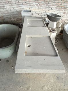 an old bathtub sitting next to a brick wall with two sinks on it's sides