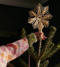 a person is decorating a christmas tree with star decorations on it and holding a stick in their hand