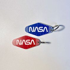 two nasa key chains are shown on a white surface