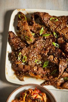 a white plate topped with meat covered in sesame seeds and garnished with green onions