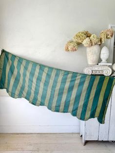 a green and white striped blanket sitting on top of a table next to a vase with flowers