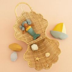 a wicker basket with a doll hanging from it and some rocks on the ground