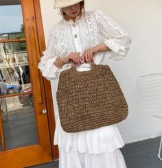 a woman in white holding a brown bag on her shoulder and wearing a straw hat