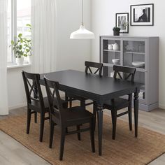 a dining room table and chairs with a rug on the floor in front of it