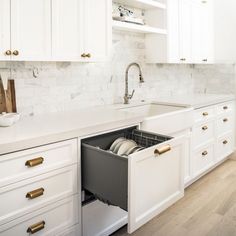 an open drawer in the middle of a kitchen counter with dishes and utensils